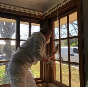 Katrina Anderson from Unique Design Painting and Decorating sanding a window